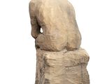 statue of a man sitting on a rock with his back to the camera