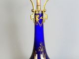 a blue vase with a gold handle on a stand