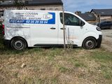 une camionnette garée devant un immeuble sur lequel est accrochée une pancarte