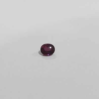 a round purple sapphire stone on a white surface