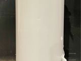 a white water tank sitting on top of a floor next to a black wall
