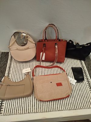 plusieurs sacs à main et un téléphone portable posés sur une table recouverte d'un tapis rayé noir et blanc