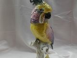 une figurine représentant un perroquet jaune et rose perché sur une branche