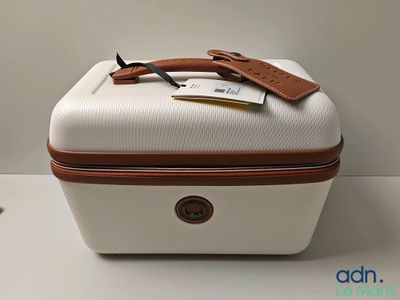 une valise blanche avec une poignée marron et une étiquette dessus