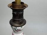 a white vase with flowers on it and a gold candle holder