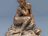 a bronze statue of a woman sitting on top of a rock