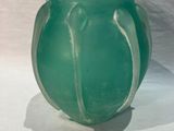 a green vase sitting on a table with a white background