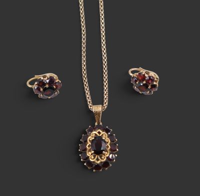 un ensemble composé d'un collier et de boucles d'oreilles en or, orné de grenats sur fond noir