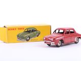 une petite voiture rouge devant une boîte de Dinky Toys