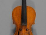 an old violin sitting on top of a table next to a gray wall