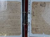 two pages of a document are on display in a glass case