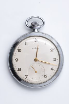 a silver pocket watch on a white surface