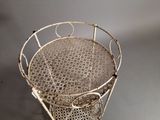 a metal chair that has a basket on top of it