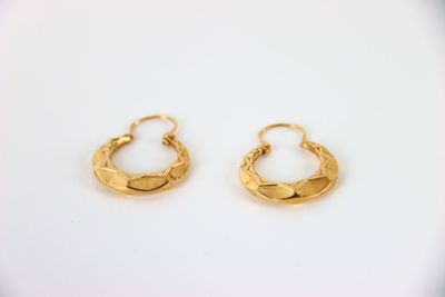 a pair of gold hoop earrings on a white surface