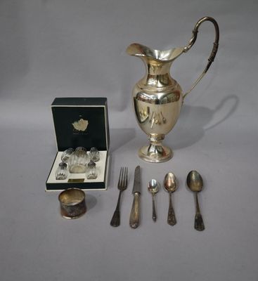 un pichet en argent, des cuillères et d'autres couverts en argent posés sur une table