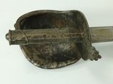 a metal object with a handle on a white surface