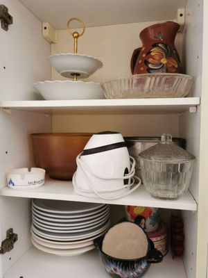 many dishes and bowls on the shelves in the cabinet