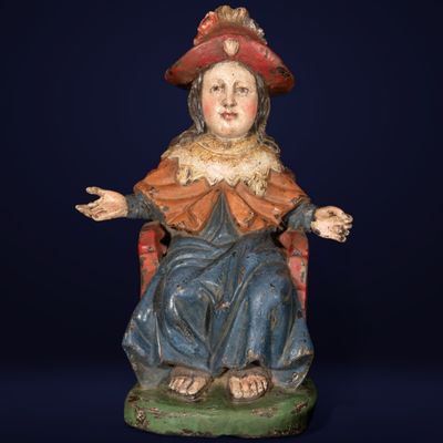 une vieille statue représentant une femme assise sur une chaise, les mains tendues