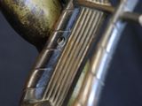 close up of a bronze sculpture of a harp on a black background