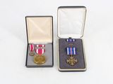 two medals and a medal in a box on a white surface
