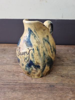 a brown and blue vase sitting on a wooden table