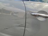 a silver car that has a broken door handle on the side of it