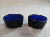 deux petits bols en verre bleu posés sur une surface blanche