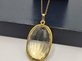 a gold plated necklace with a clear glass pendant on a gold chain