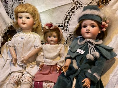 trois poupées assises l'une à côté de l'autre sur une table