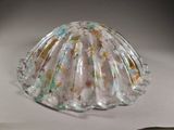 un objet en verre en forme de coquille posé sur une surface blanche