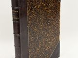 an old book sitting on top of a white table next to a white wall