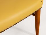 a close up of a yellow leather chair with wooden legs