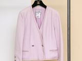 une veste rose suspendue à un cintre devant un mur beige