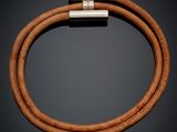 a brown leather bracelet with a silver clasp on a black background
