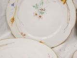 three plates with flowers are sitting on a white table cloth