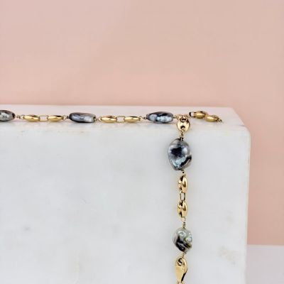 necklace with black and gold beads on a white marble block
