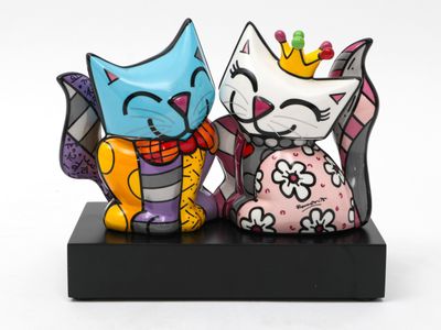 two figurines of cats that are sitting on a stand