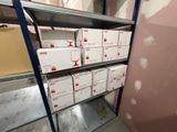 Des boîtes sont empilées sur une étagère dans une pièce aux murs roses.
