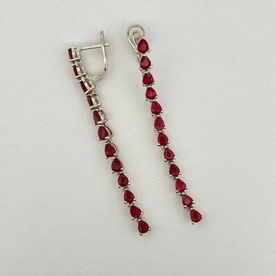 a pair of earrings with red stones on a white surface