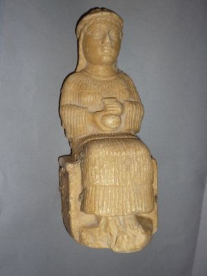 une statue représentant une femme assise sur un rocher
