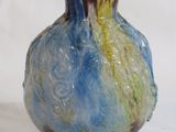 a blue and yellow vase sitting on a white surface