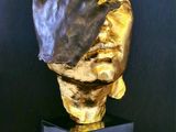 a gold sculpture of a hand holding a human hand