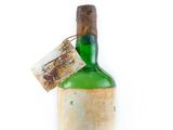 an old bottle with a tag on it sitting on top of a white surface
