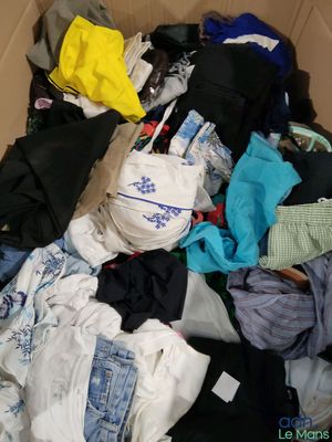 un carton rempli de vêtements et des vêtements par terre