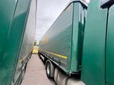 two green semi trucks parked side by side on the road