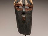 a close up of a wooden mask on a stand