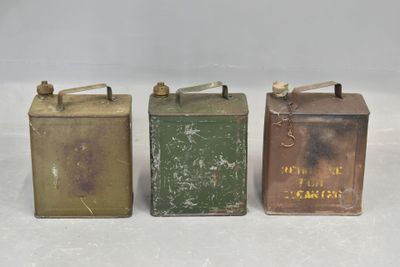 three old tin cans are lined up on a white surface