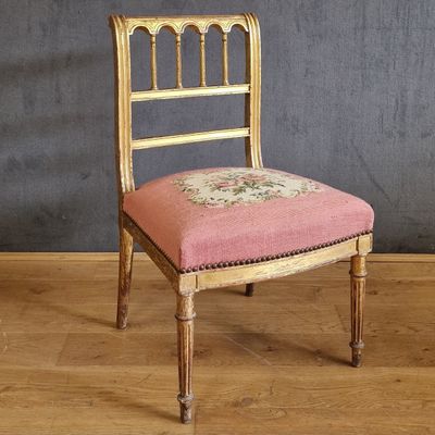une chaise avec un coussin rose, placée devant un mur gris