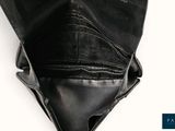 a black purse that is sitting on a white surface
