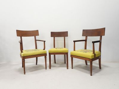 two wooden chairs with yellow upholstered cushions in a white room